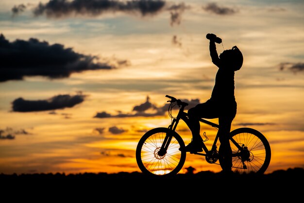 日没時のシルエットを休んでサイクリスト。アクティブな屋外スポーツコンセプト