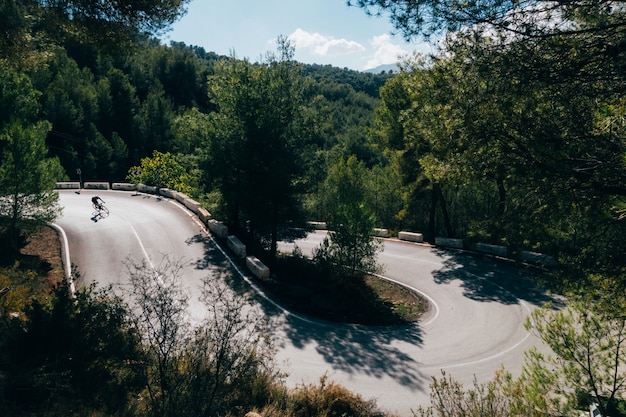 Cyclist riding a bike at sunset in a mountain road