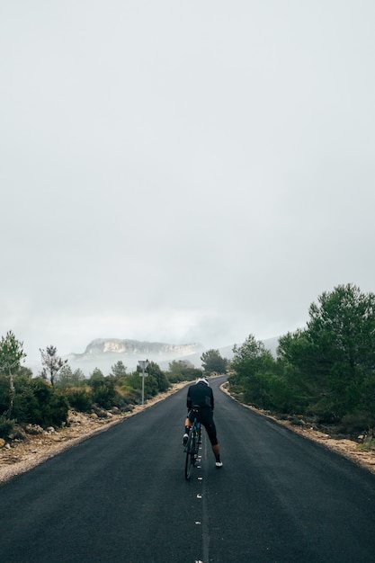 Free photo cyclist riding a bike at sunset in a mountain road