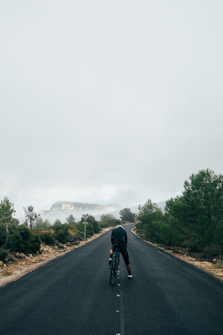 Free Photo cyclist riding a bike at sunset in a mountain road