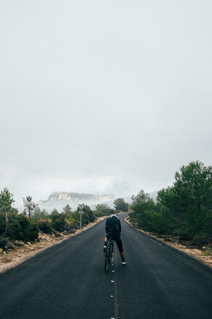 Cyclist riding a bike at sunset in a mountain road