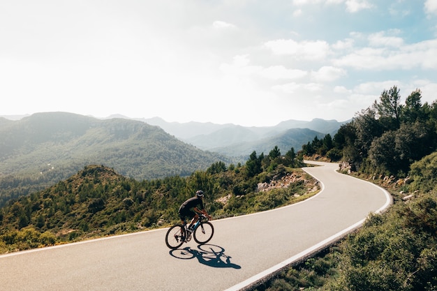 Cyclist riding a bike at sunset in a mountain road