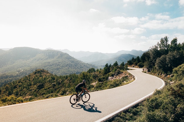 Ciclista in sella a una bicicletta al tramonto in una strada di montagna