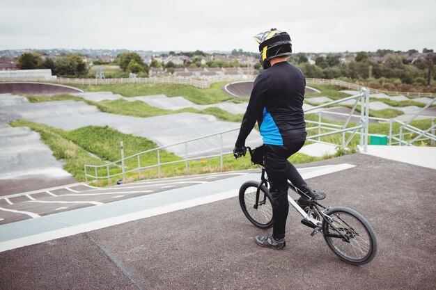 Cyclist standing with BMX bike at starting ramp