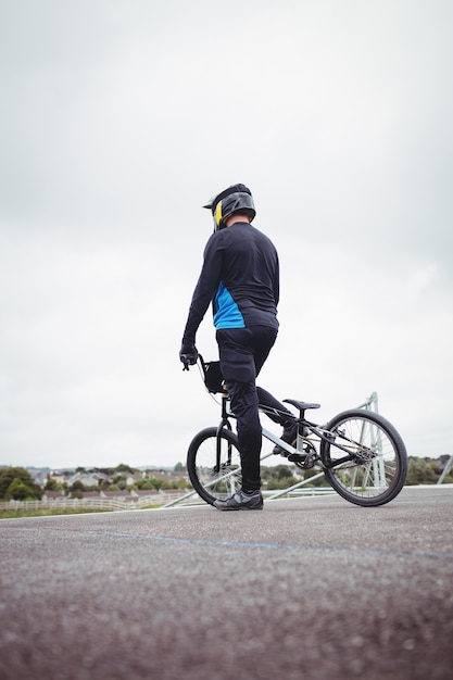 Free photo cyclist standing with bmx bike at starting ramp