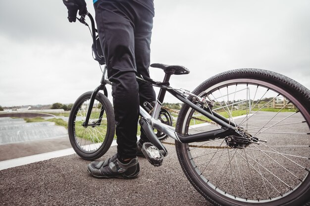 Cyclist standing with BMX bike at starting ramp