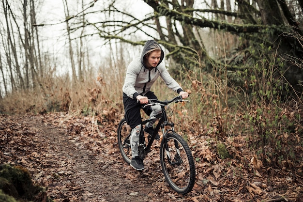 숲에서 후드 탑 승마 자전거를 착용하는 자전거 타는 사람