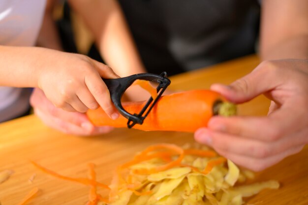 Dad and child peeling a carrot close-up