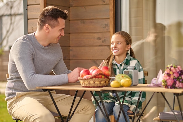 Dad and daughter talking at table on veranda