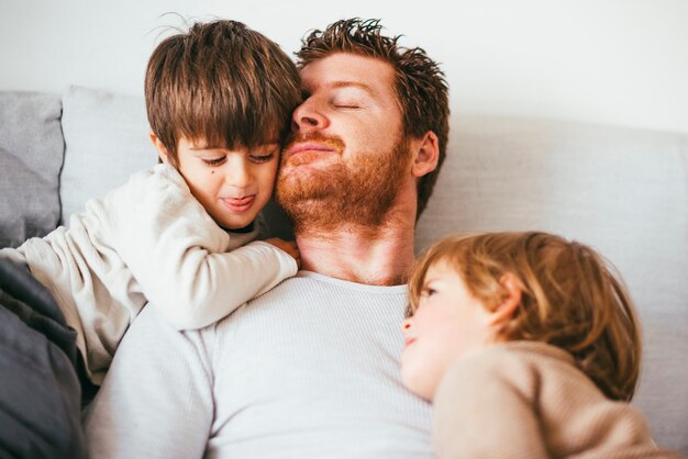 Dad head leans against son on sofa