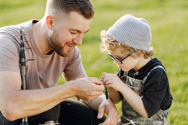 Dad and his child boy spend time outdoors together. Curly toddler boy wearing a khaki overall. Boy listening his father