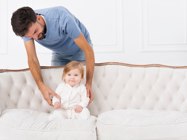 Free photo dad holding baby on sofa