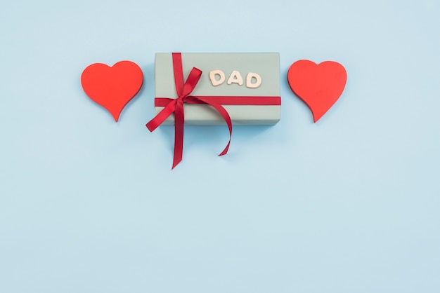 Dad inscription with gift box and hearts on table