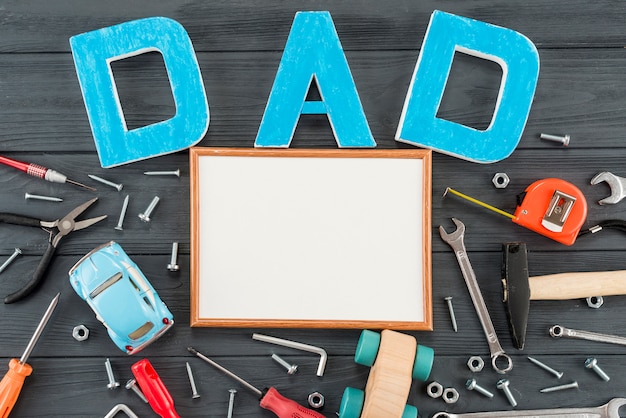 Dad inscription with tools and blank frame on table