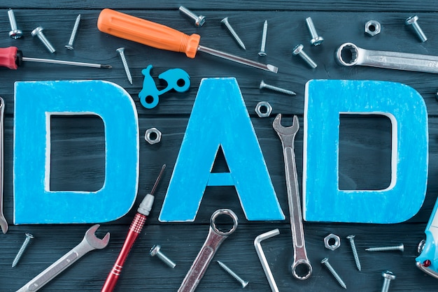 Dad inscription with tools on blue table