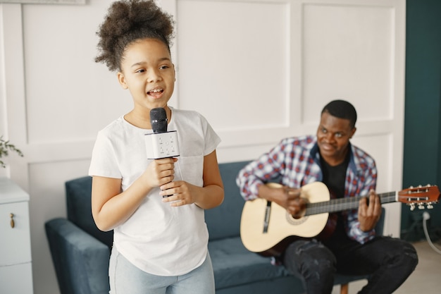 Foto gratuita papà è seduto con una chitarra e una figlia con un microfono