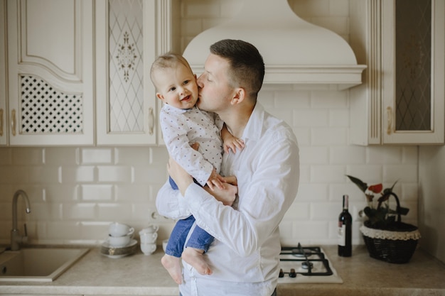 Dad kisses baby son in the kitchen