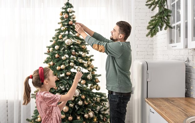 お父さんと小さな娘が一緒にクリスマスツリーを飾ります