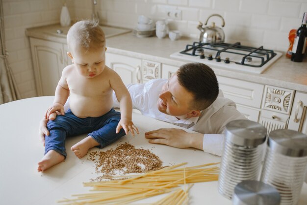 Dad looks at his little son sitting on the table