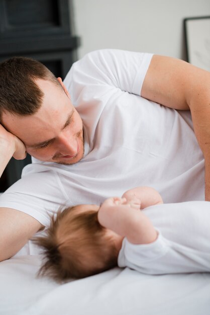 Dad lying with baby on bed