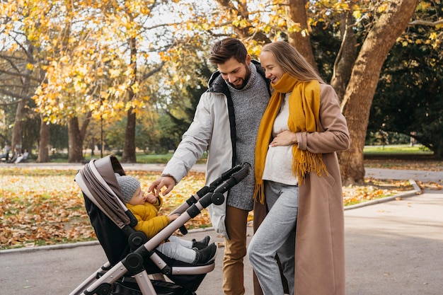 Dad and mom with child in stroller outdoors