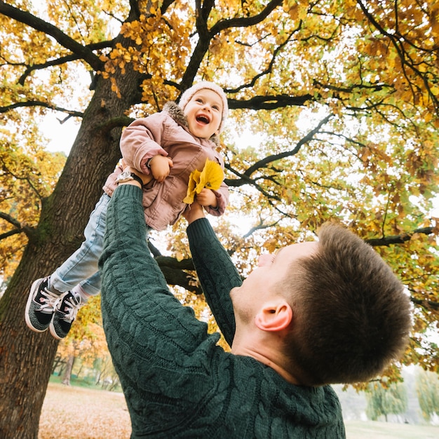 Dad playing with daughter in autumn forest