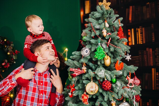 お父さんは小さなお子さんと一緒に、クリスマスと新年の服装の部屋に座ります