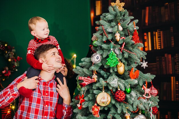 아빠는 크리스마스와 새해 옷을 입고 방에 그의 작은 아들과 함께 포즈