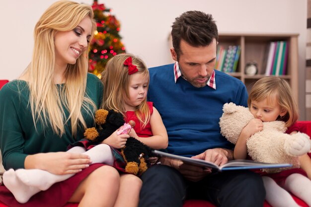 Dad reading book for his daughters in christmas