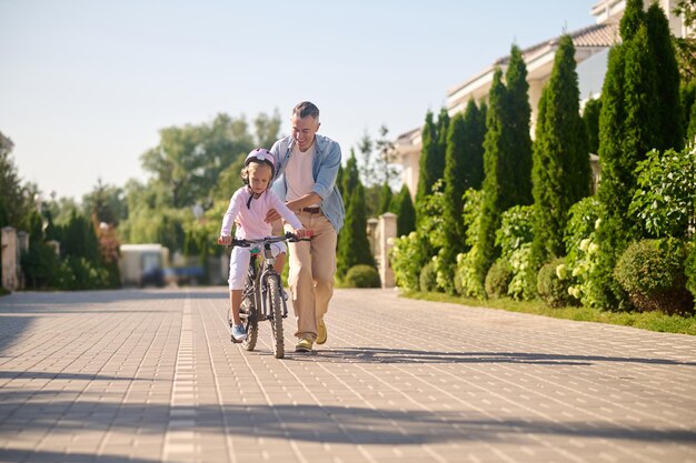 Dad riding a bike with his daughter sitting on it