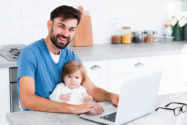 Dad smiling while working on laptop with baby