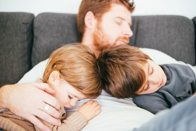 Free photo dad snoozing with cute sons on sofa