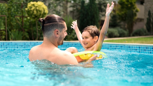 Foto gratuita papà che nuota con suo figlio felice in piscina