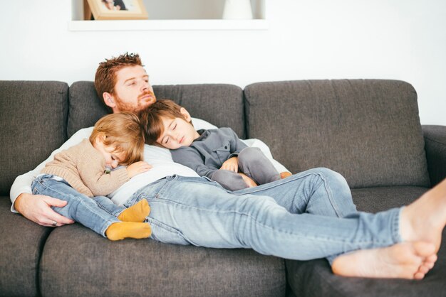 Dad taking nap with sons on sofa