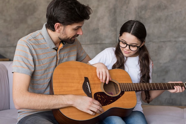 Dad teaching girl to play guitar