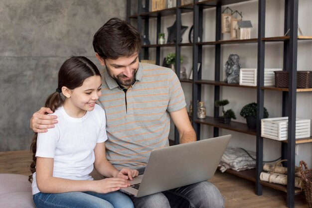 Dad teaching girl to use laptop
