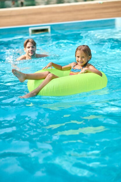 Dad teaching his daughter swimming in a swimming pool