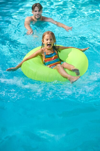 Dad teaching his daughter swimming in a swimming pool