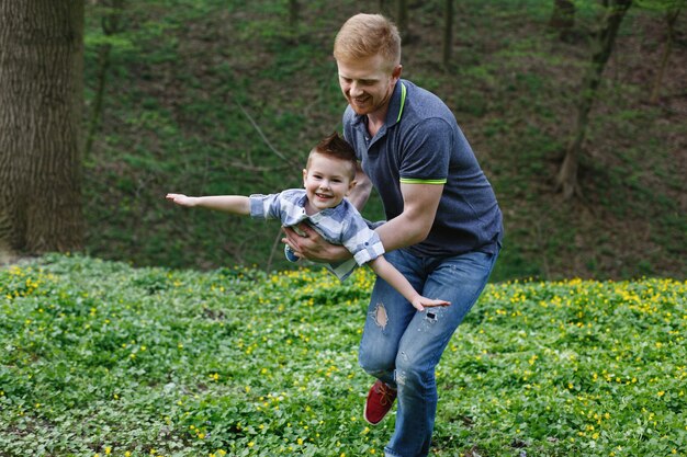 Dad whirls his son like an airplane playing in the green park
