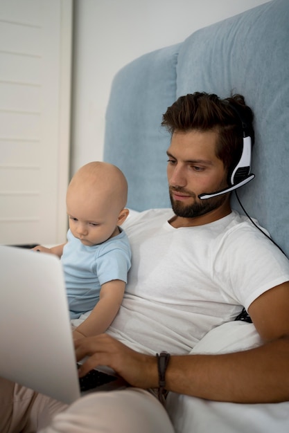 Foto gratuita papà che lavora da casa durante la quarantena con il bambino