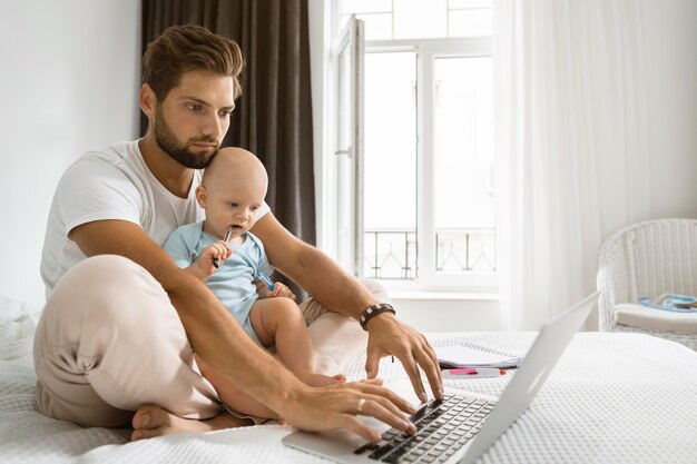 Dad working on laptop from home during quarantine with child