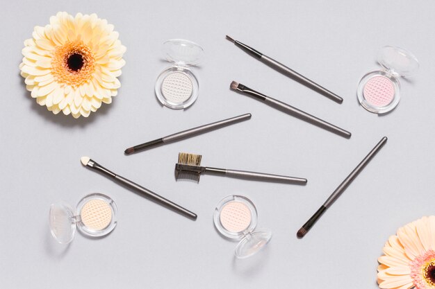 Daisies near applicators and eye shadow