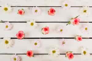 Free photo daisy and rose heads on timber tabletop