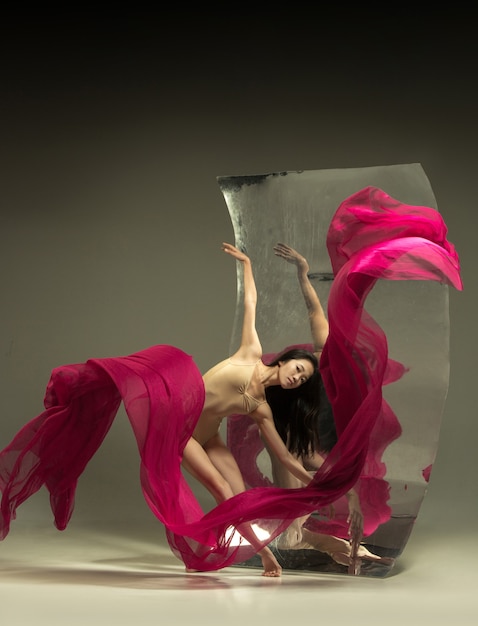 無料写真 火で踊る。鏡付きの茶色の壁にモダンなバレエダンサー。表面での錯覚の反射。柔軟性の魔法、生地による動き。クリエイティブアートダンス、アクション、インスピレーションのコンセプト。