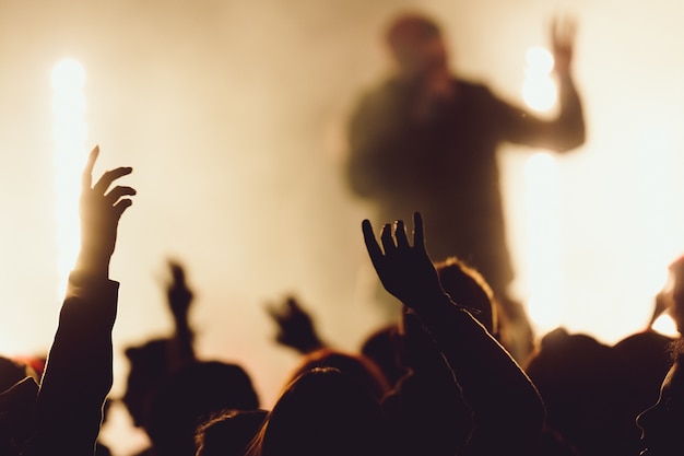 Foto gratuita ballando ad un concerto mentre il cantante si esibisce circondato dalle luci