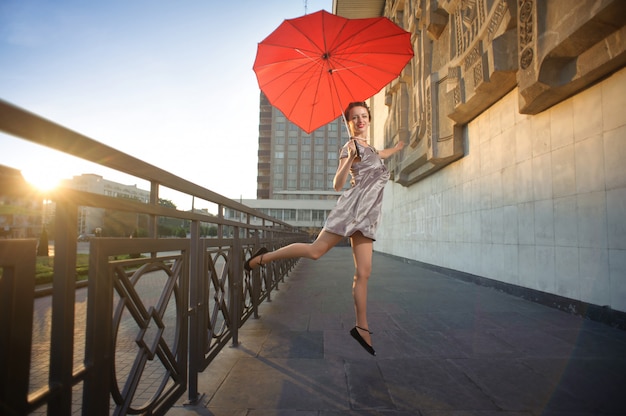 Dancing girl holding heart-shaped red umbrella.