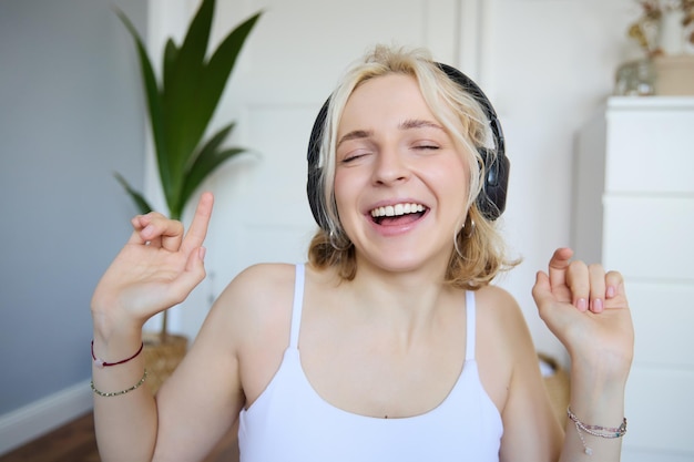 Dancing girl listens to music woman wears wireless headphones and enjoys sound quality sings