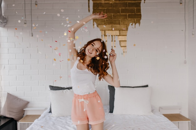 Ragazza che balla in indumenti da notte alla ricerca. modello femminile sorridente in pantaloncini in posa in camera da letto.