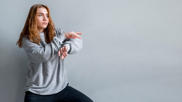 Dancing young woman against grey wall