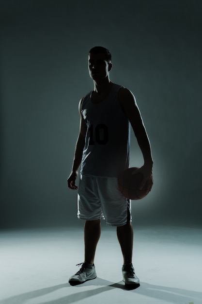 Dark background with basketball player posing